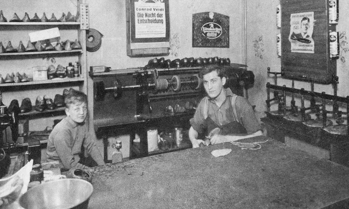 Altes Foto einer Schumacherwerkstatt mit einem Mann und einem Jungen.